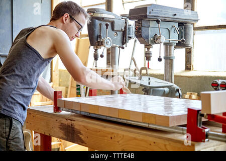 Seitenansicht der Tischler Auftragen von Leim auf Holzbrett in Schreinerei Stockfoto