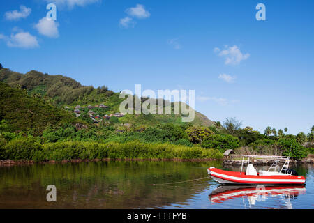 Französisch Polynesien, die Insel Moorea. Eine Bootsfahrt entlang der Küste mit Blick auf die Legenden Resort Bungalows entlang der Berg im Hintergrund verankert. Stockfoto