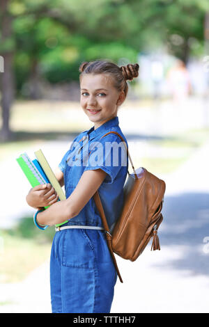 Nette junge Mädchen mit Stack von Notebooks auf dem Weg zur Schule Stockfoto