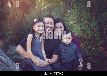 Portrait von Happy Family gegen Pflanzen im Park Stockfoto
