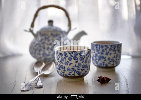 Tasse mit heißem Aufguss von Sternanis und Teekanne auf weiße Holztisch. Stockfoto