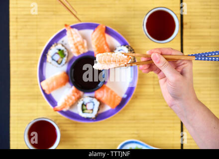 Frau mit Stäbchen erreichen für Sushi am Restaurant Fach Stockfoto