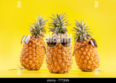 Kreative Ananas suchen mit Sonnenbrille und Shell auf gelbem Hintergrund, Sommerurlaub Strand Idee design pattern, Raum schliessen Nach oben kopieren Stockfoto