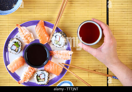 Frau mit Stäbchen erreichen für Sushi am Restaurant Fach Stockfoto