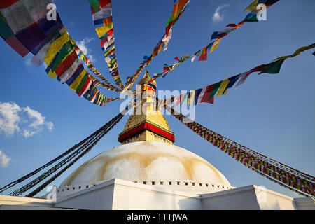 Low Angle View von Boudhanath Stupa mit bunten Gebetsfahnen gegen den blauen Himmel Stockfoto