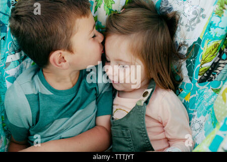 Junge küssen Schwester beim Liegen in einer Hängematte Stockfoto