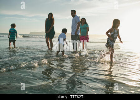 Familie im Meer gegen Himmel bei Sonnenuntergang Stockfoto