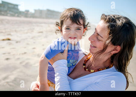 Portrait von Happy Boy von Mutter am Strand während der sonnigen Tag durchgeführt werden Stockfoto