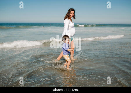 Mutter und Sohn im Meer gegen den klaren Himmel Stockfoto