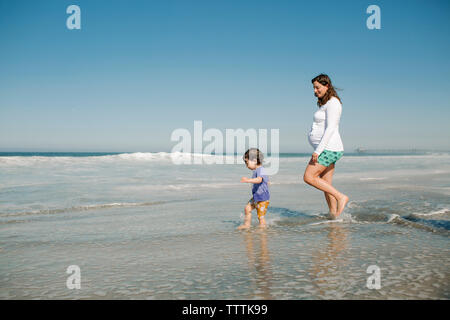 Seitenansicht von Mutter und Sohn im Meer gegen blauen Himmel Stockfoto