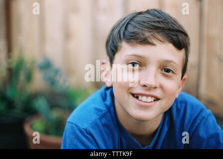 Portrait von lächelnden Jungen im Hinterhof gegen Holzzaun Stockfoto