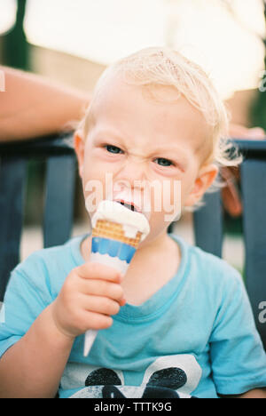 Portrait der junge Eis essen beim Sitzen auf der Werkbank Stockfoto