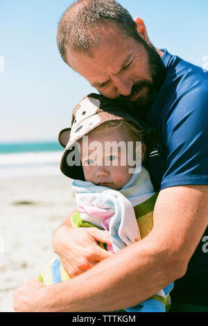 Close-up von Vater, Sohn sitzend auf Sand am Strand Stockfoto