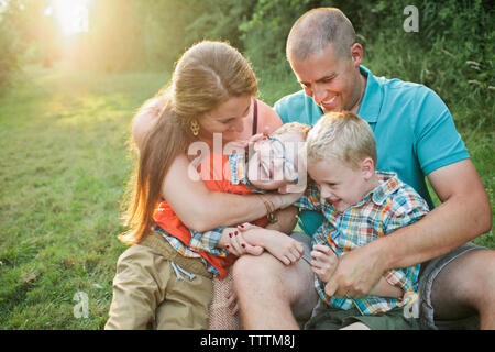 Glückliche Familie sitzt auf der Wiese im Wald Stockfoto