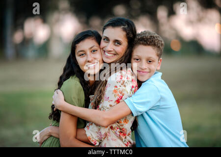 Portrait der liebevollen Mutter und Kinder umarmen im Park Stockfoto