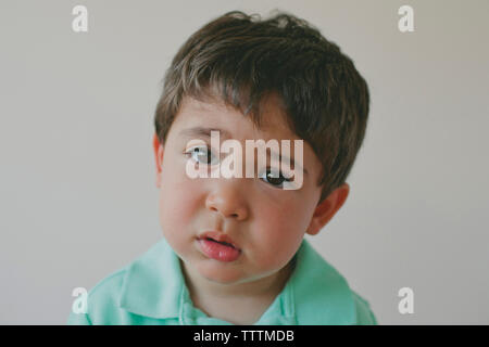 Close-up Portrait von Sad baby boy gegen grauer Hintergrund Stockfoto