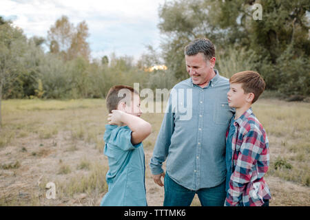 Vater mit Söhnen während stehend auf dem Feld im Park Stockfoto