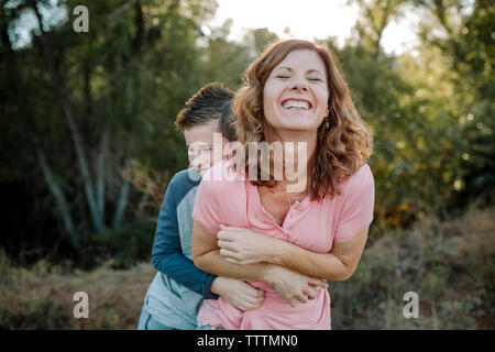Happy Sohn kitzeln Mutter, während im Wald Stockfoto