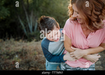 Happy Sohn kitzeln Mutter, während im Wald Stockfoto
