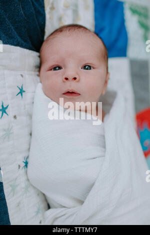 Portrait von neugeborenen Baby boy in Decke liegend auf Bett zu Hause gewickelt Stockfoto