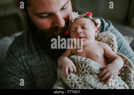 Nahaufnahme des bärtigen Vater die niedlichen schlafenden Tochter Tiara tragen, während sie auf dem Sofa zu Hause sitzen Stockfoto