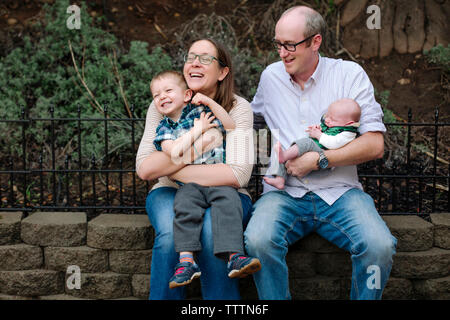 Glückliche Eltern mit Kinder im Park sitzen Stockfoto