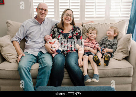 Glückliche Familie auf der Couch zu Hause sitzen Stockfoto