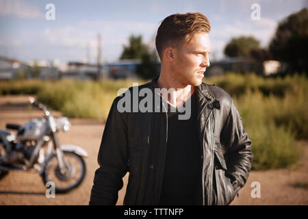 Biker weg schauen beim Stehen auf Feld Stockfoto