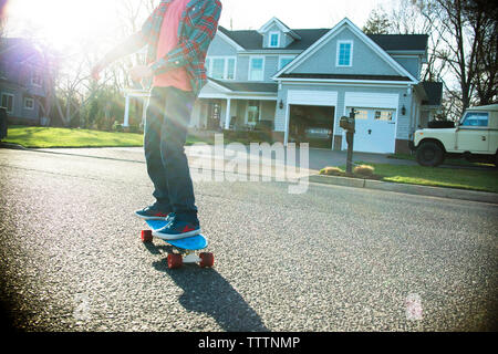 Niedrige Abschnitt der Boy skateboarding auf der Straße gegen Haus Stockfoto