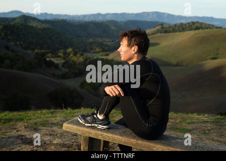 Nachdenklicher Mann sitzt auf Holz- sitz Stockfoto