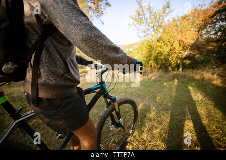 Mittelteil der männlichen Athleten auf dem Fahrrad im Feld Stockfoto