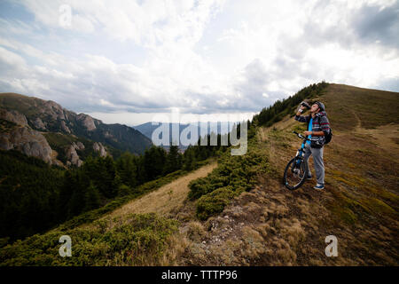 Radfahrer Trinkwasser beim Stehen auf den Berg mit dem Fahrrad Stockfoto