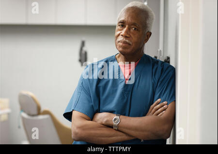 Portrait von Arzt mit verschränkten Armen lehnte sich an der Wand im Krankenhaus Stockfoto