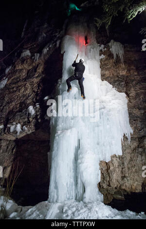 Low Angle View von eiskletterer Klettern an gefrorenen Wasserfall Stockfoto