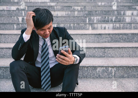 Asiatische Geschäftsleute mit Kopfschmerzen oder Migräne im Rathaus nach der Arbeit Bilder der jungen Unternehmer, die müde sind, Stress, Krise, Depression, failu Stockfoto