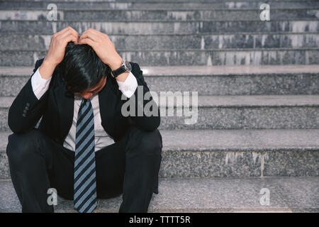 Asiatische Geschäftsleute mit Kopfschmerzen oder Migräne im Rathaus nach der Arbeit Bilder der jungen Unternehmer, die müde sind, Stress, Krise, Depression, failu Stockfoto