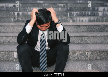 Asiatische Geschäftsleute mit Kopfschmerzen oder Migräne im Rathaus nach der Arbeit Bilder der jungen Unternehmer, die müde sind, Stress, Krise, Depression, failu Stockfoto