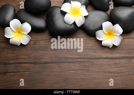 Wellness Steine und plumeria Blumen auf Holz- Hintergrund, Ansicht von oben Stockfoto