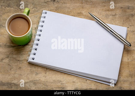 Leere Spirale Art Skizzenbuch gegen strukturierte Rinde Papier mit einer Tasse Kaffee Stockfoto