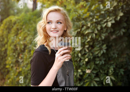 Schöne Mädchen mit Tasse Kaffee auf grüne Blätter Hintergrund Stockfoto