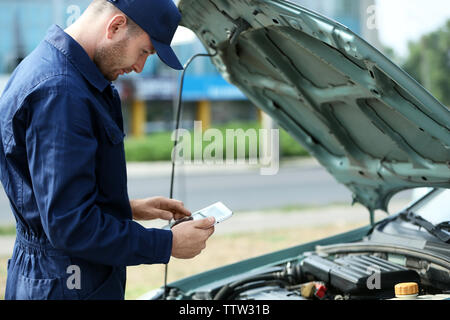 Mechaniker vor einem offenen Wagen Haube mit dem Tablet Stockfoto