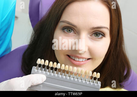 Zahnarzt Überprüfung und Auswahl der Farbe der jungen Frau Zähne Stockfoto