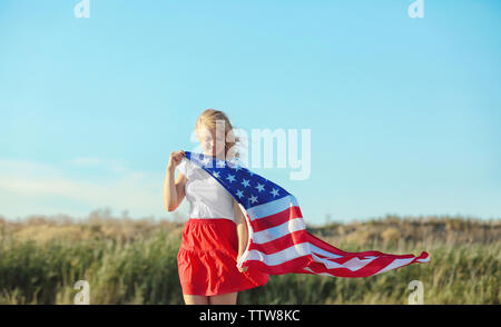 Junge Frau mit der amerikanischen Flagge auf blauen Himmel Hintergrund Stockfoto