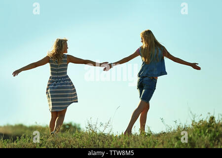 Zwei junge Frauen, die auf blauen Himmel Hintergrund Stockfoto