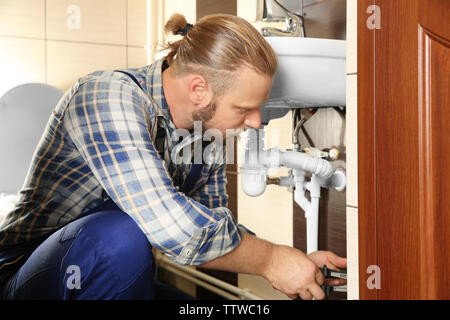 Gutaussehenden Klempner Instandsetzung Waschbecken Rohre im Bad, Ansicht schließen Stockfoto