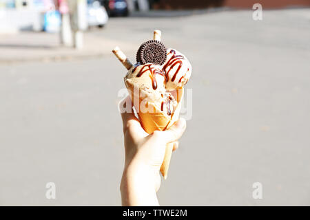 Weibliche hand Eis mit Schokoladensauce und Cookies Stockfoto