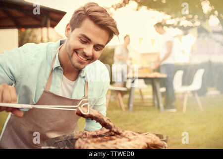 Hübscher junger Mann Vorbereitung Grill Steaks vom Grill Stockfoto