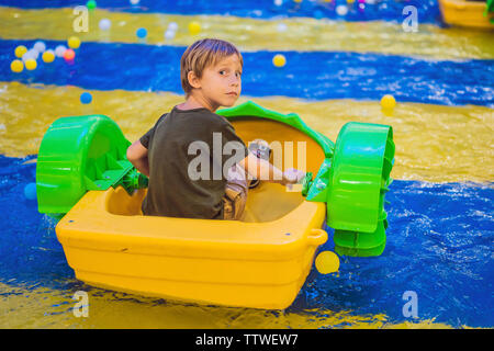 Glückliche junge Junge auf dem Boot genießen, spielen auf Vergnügungspark Stockfoto