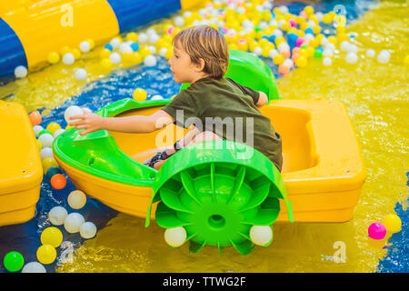 Glückliche junge Junge auf dem Boot genießen, spielen auf Vergnügungspark Stockfoto