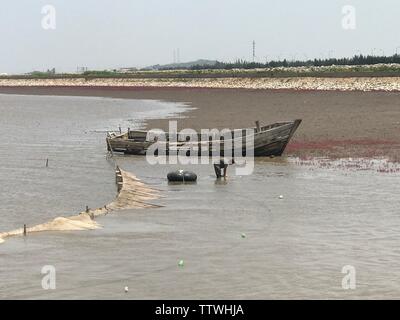 Die Fischer, die die Fischerei an der Küste machen, und verfallene Boote sind auf dem Strand angedockt. Stockfoto